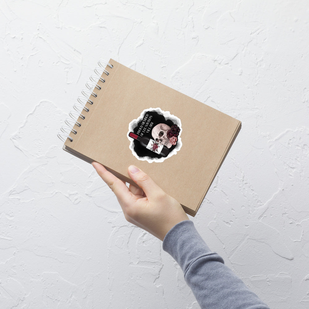 Hand holding a spiral-bound notebook with a sticker on a light gray textured surface